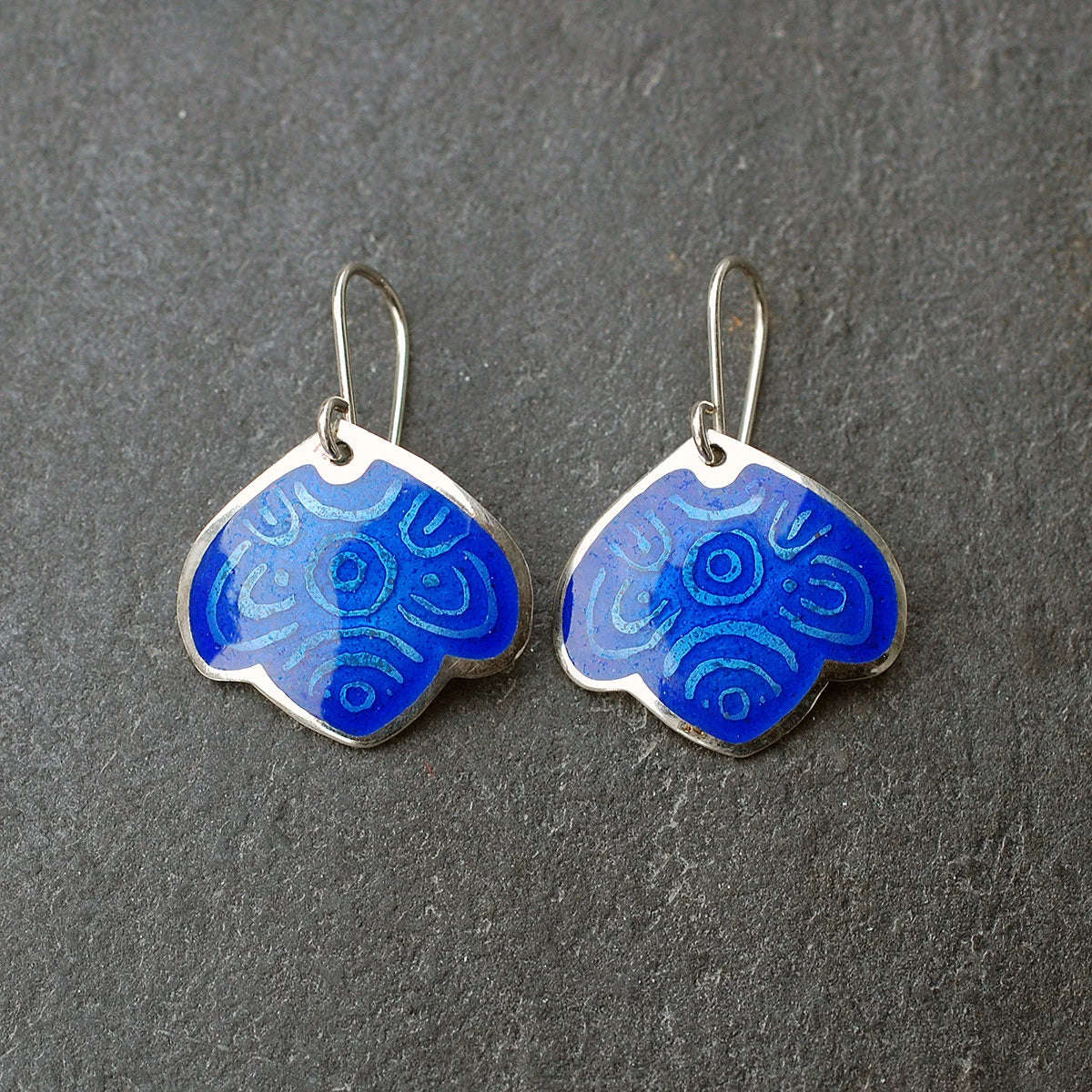 Blue leaf enamel earrings on a grey slate background.