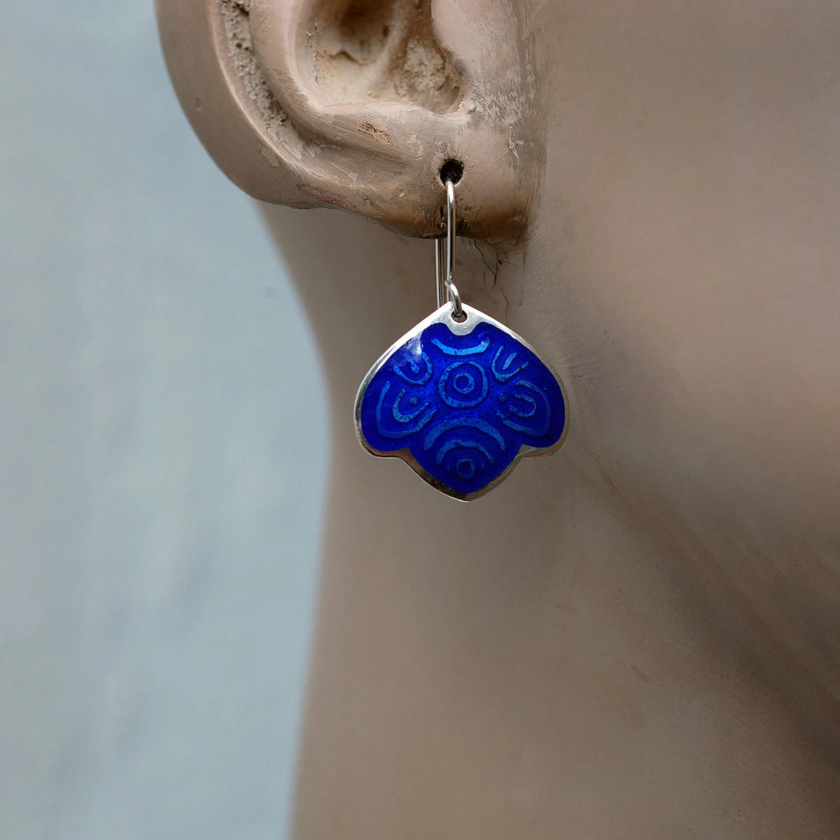 Blue leaf enamel earrings worn by a mannequin.