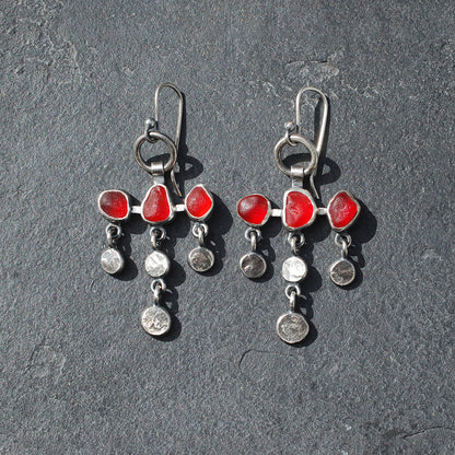
Dot and dangle red sea glass earrings on a grey slate background.
